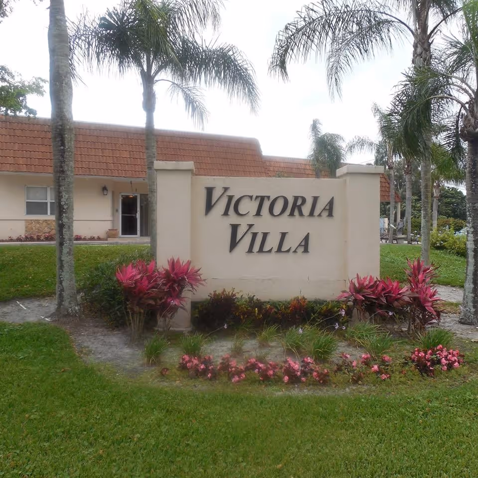 Victoria Villa entrance sign with landscaped front yard and palm trees.