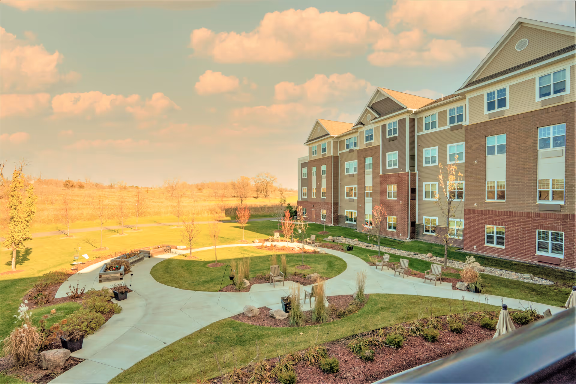 Exterior view of a senior living facility with landscaped garden and seating areas.