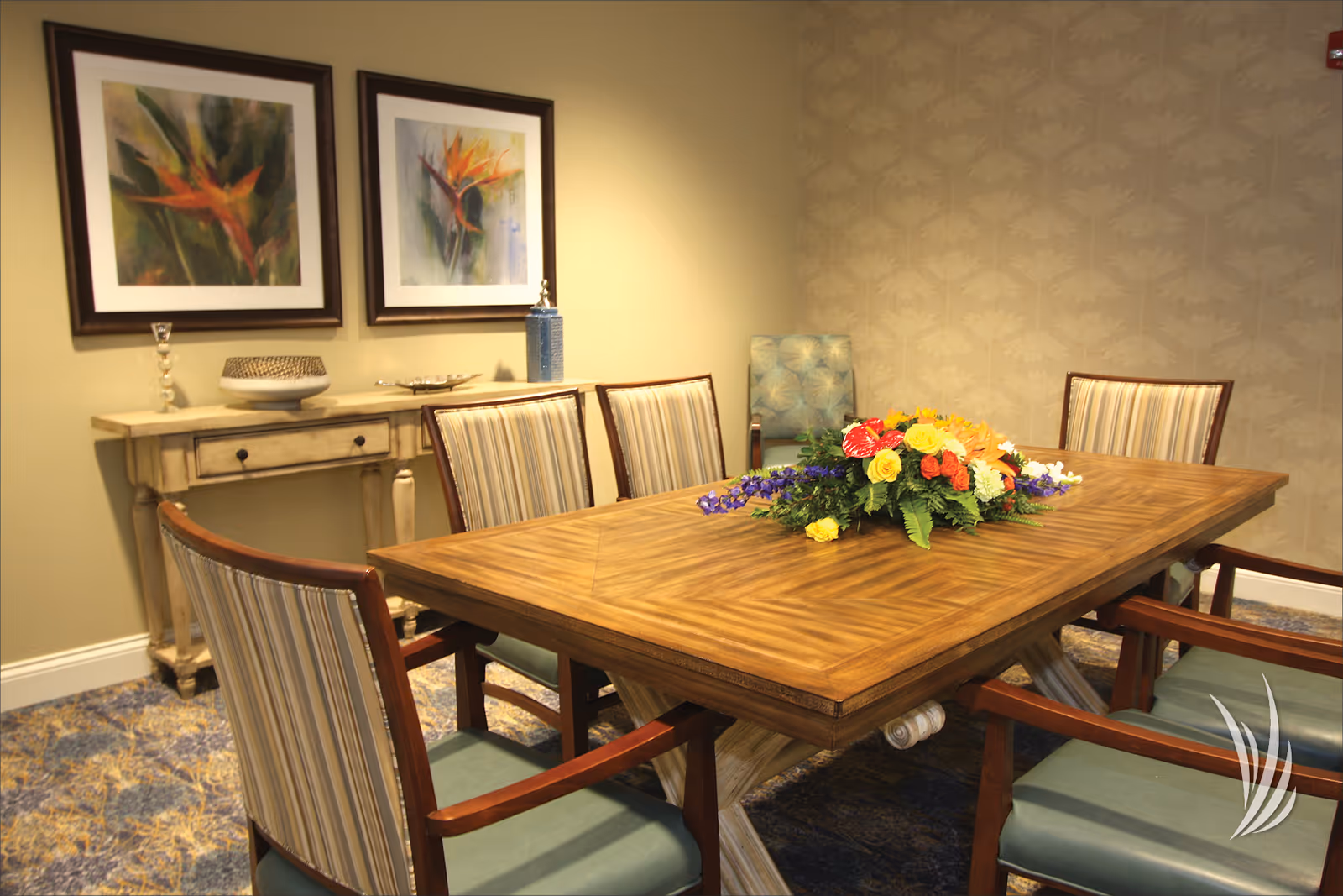 A dining area with a wooden table, floral centerpiece, and framed artwork on the walls.