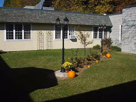 Exterior view of a single-story facility with lawn, pumpkins, and lampposts.