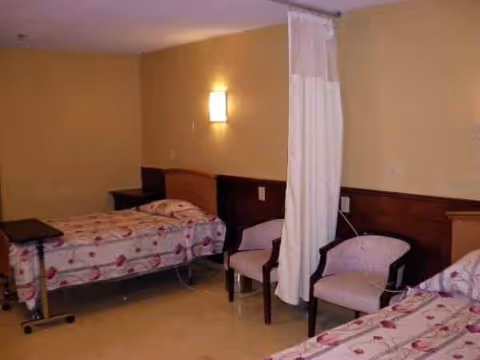 Shared senior living bedroom with two beds, privacy curtain, and seating area.