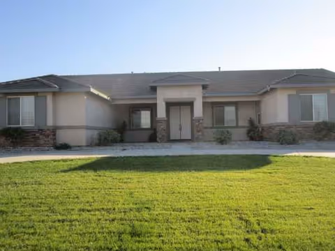 Single-story senior living facility exterior with front entrance and green lawn.