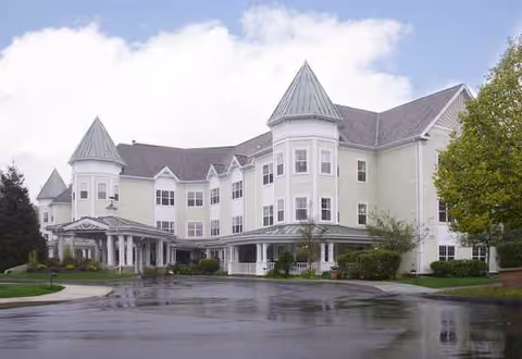 Sunrise of Cohasset exterior, a light-colored turreted building with a covered entrance.