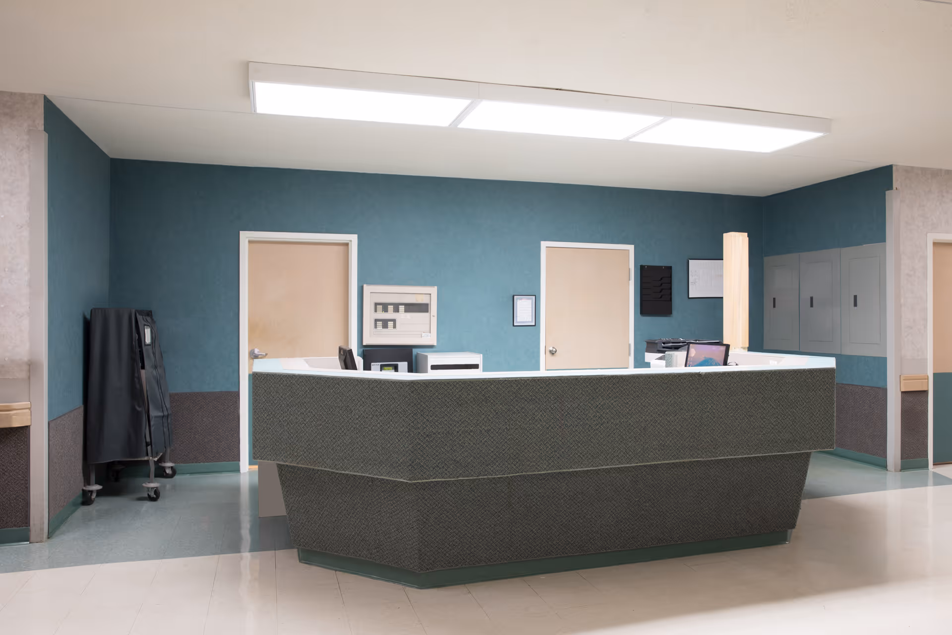 Reception desk and nurse station in an interior hallway with teal walls and closed doors.