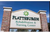 Outdoor sign for Plattsburgh Rehabilitation & Nursing Center mounted on a brick structure with a blue sky background.