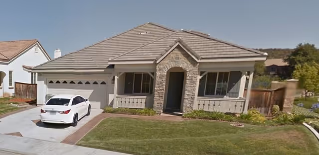 Front view of a single-story residential care facility with stone entry and driveway.