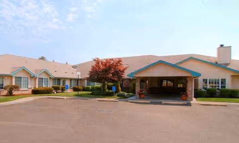 Exterior view of a single-story senior living facility with a front entrance and landscaping.