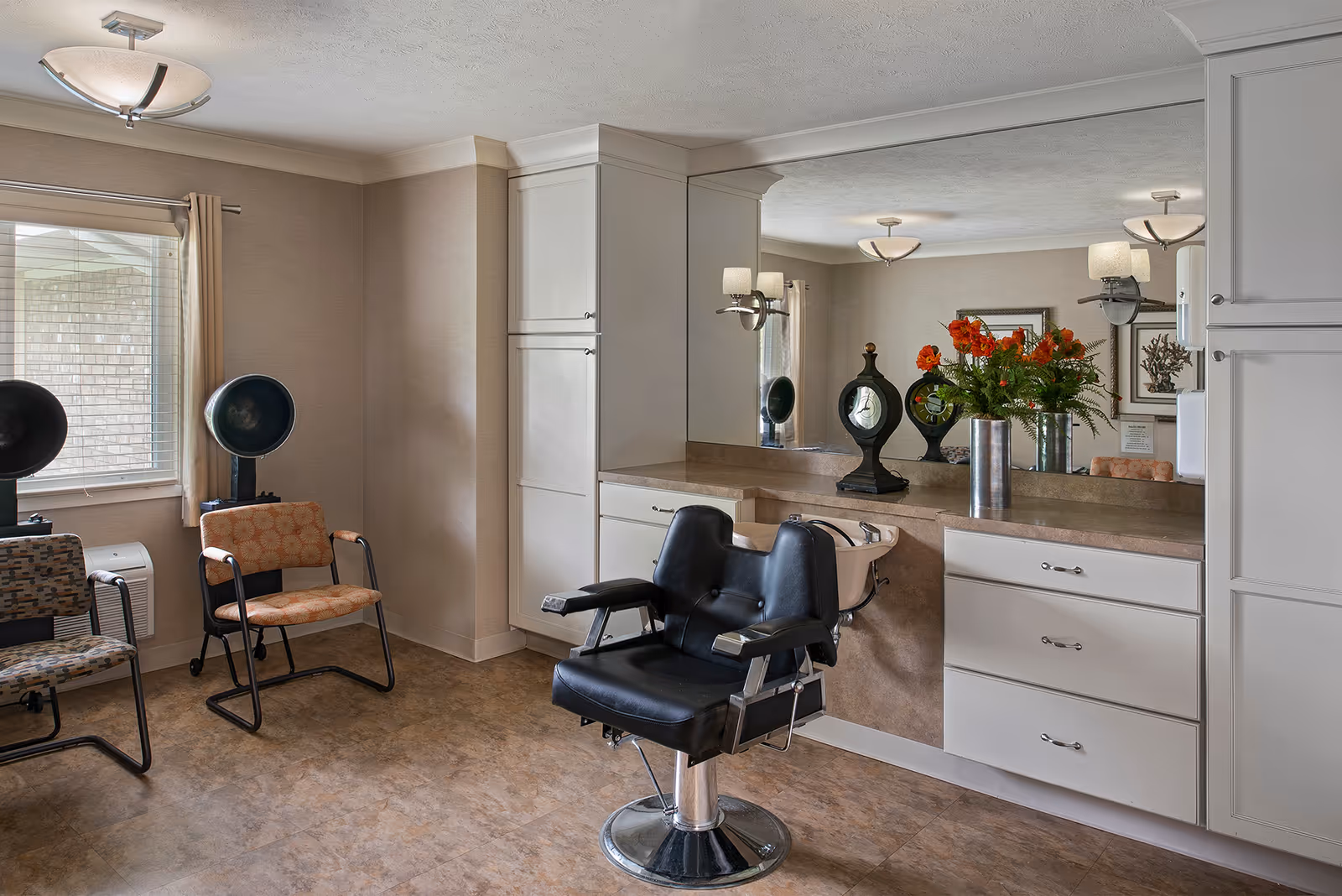 Interior salon with a black styling chair, counters and mirror, drying stations and waiting chairs.
