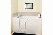 A white bathtub with grab bar and framed picture in a small bathroom.