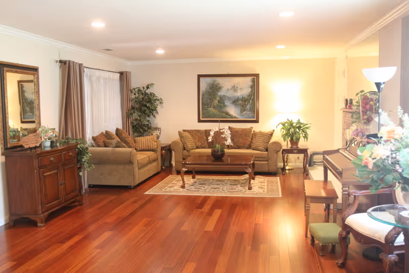 Spacious living room with hardwood floors, two sofas around a coffee table, a painting on the wall and a piano to the right.