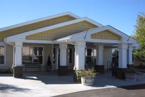 Front entrance of Prairie House Assisted Living and Memory Care with columns and seating.