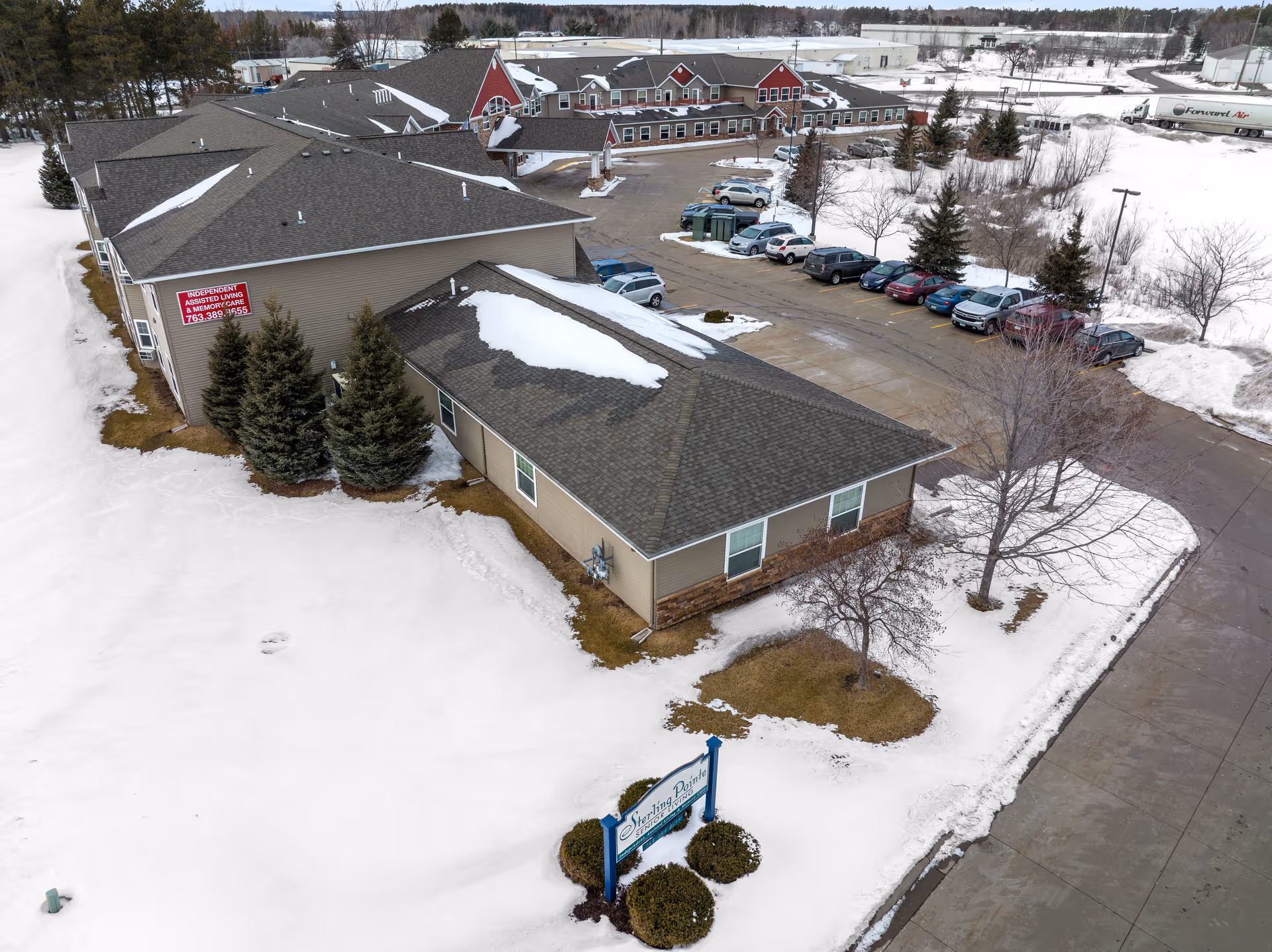 Aerial view of Sterling Pointe Senior Living facility with snow-covered ground and parked cars.