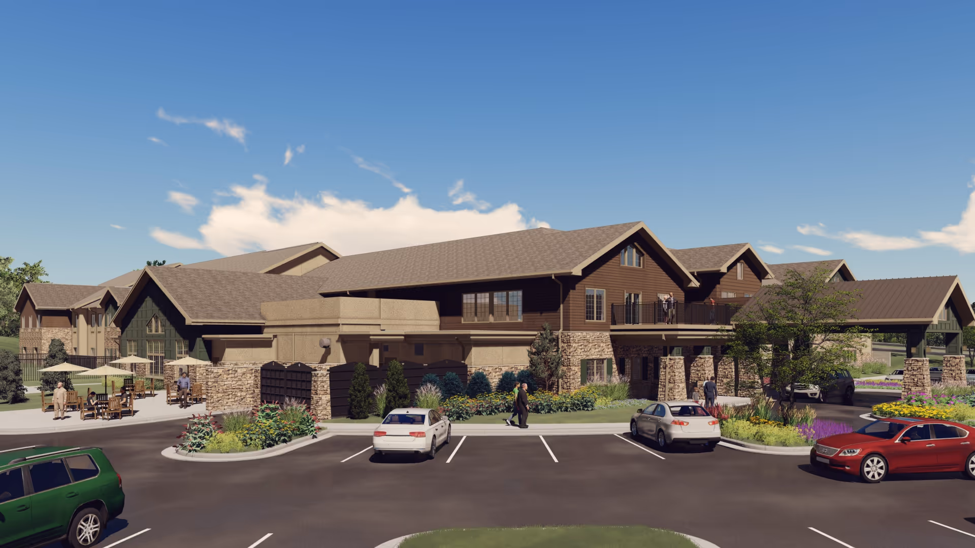 Front exterior of a large two-story senior living facility with a parking lot, landscaping, and outdoor seating under a blue sky.