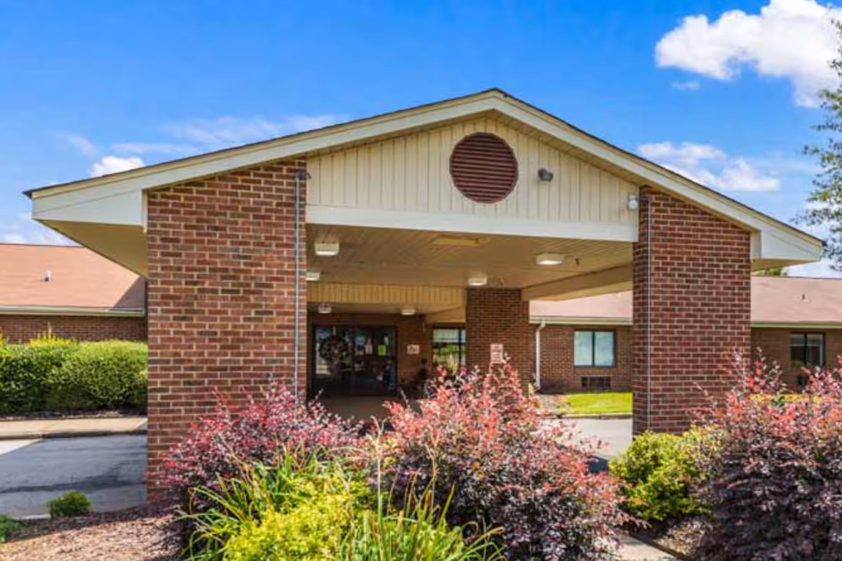 Brick-faced building entrance with a covered drop-off and landscaped approach.