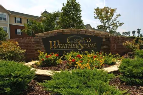 Entrance sign Weatherstone Spring, with brick surround and colorful flower beds.