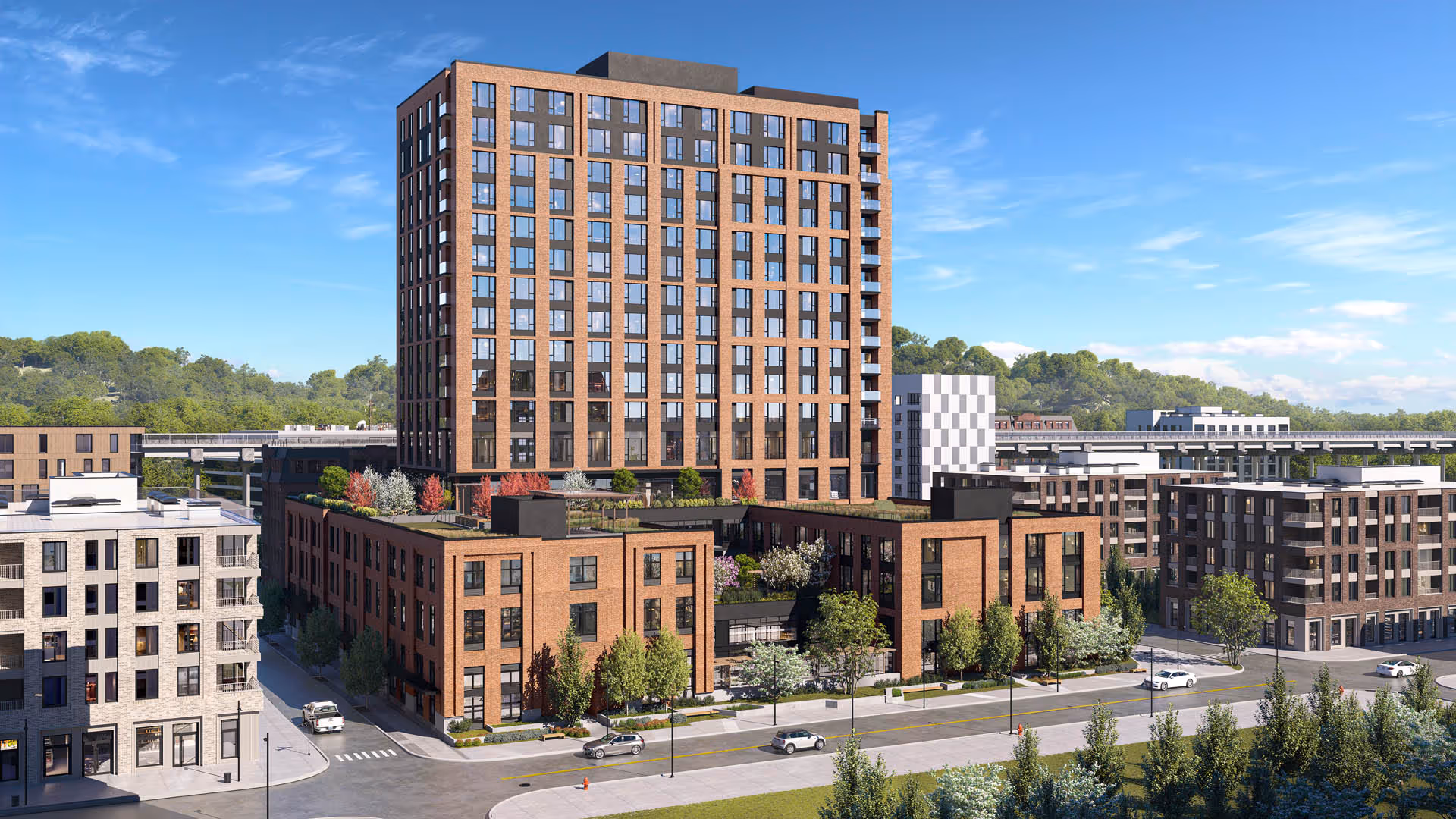 Exterior view of a multi-story brick senior living building with a taller tower above a lower podium and street-level trees and cars.