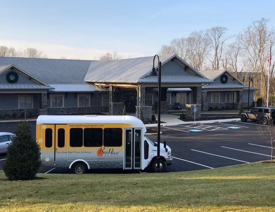 Exterior view of BeeHive Homes of Springboro with a yellow bus in the parking lot