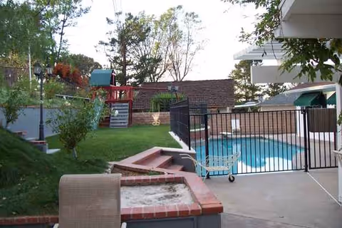 Outdoor pool area at a senior living facility with seating and greenery.