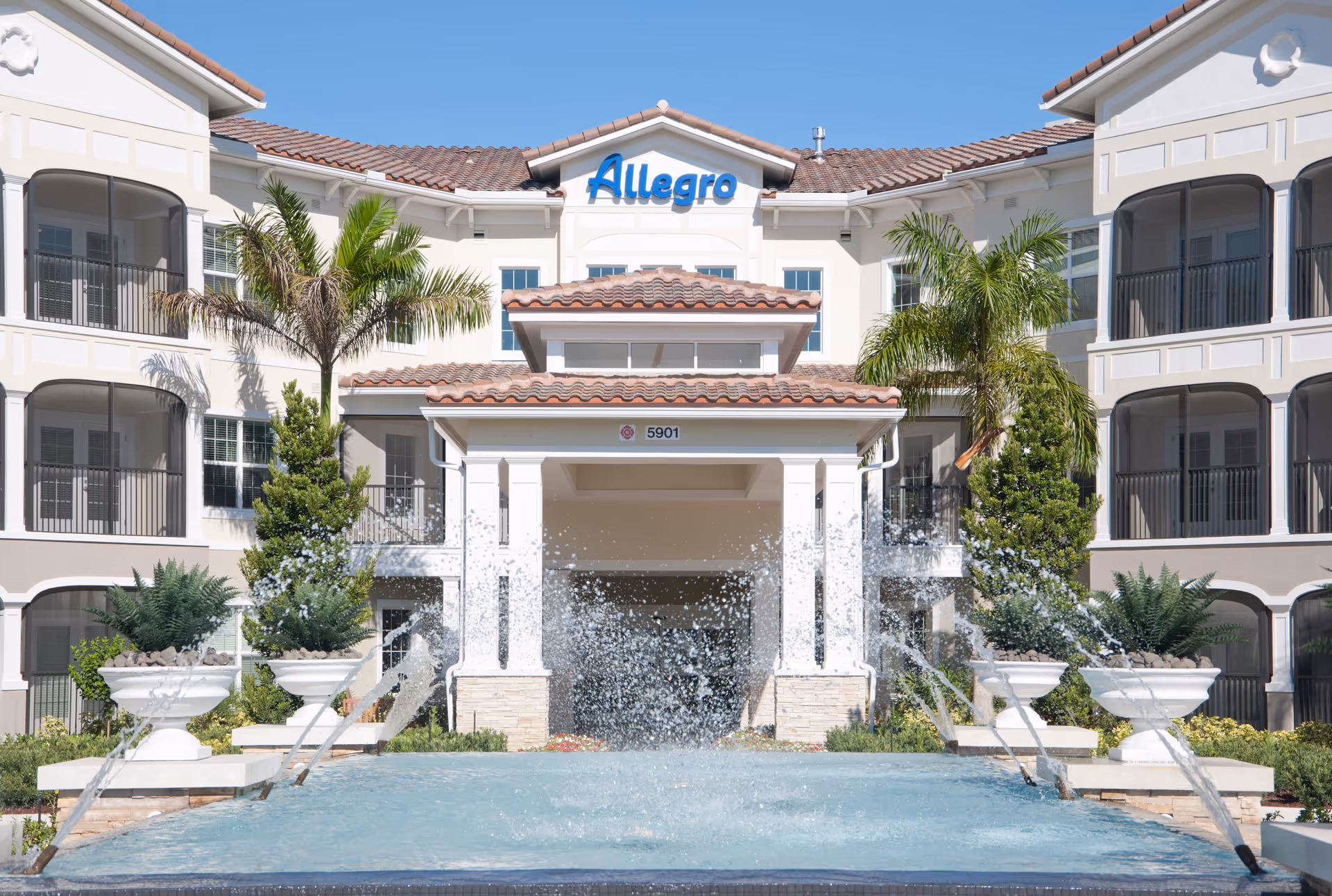 Exterior view of Allegro Senior Living facility featuring a fountain and landscaping.