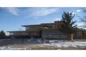 Two-story Forgetmenot Care Home exterior with large windows, snow on the ground, and a tree.