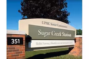 Entrance sign for Sugar Creek Station at UPMC Senior Communities mounted between brick pillars with the address number 351.