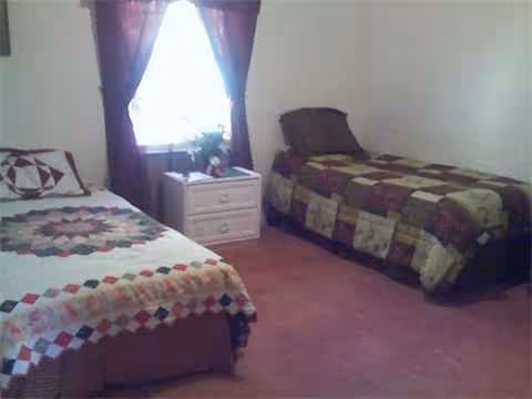 Two beds with patchwork quilts in a bedroom.