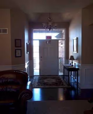 Entryway of Falkirk Assisted Living of Monroe with front door, rug, and side table.