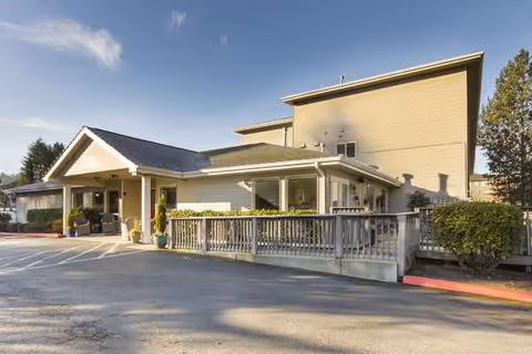 Exterior view of Cogir of Bothell Memory Care building with ramp, porch, and potted plants.