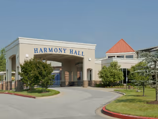 Exterior view of Lorien Harmony Hall entrance with curved driveway and landscaped trees.
