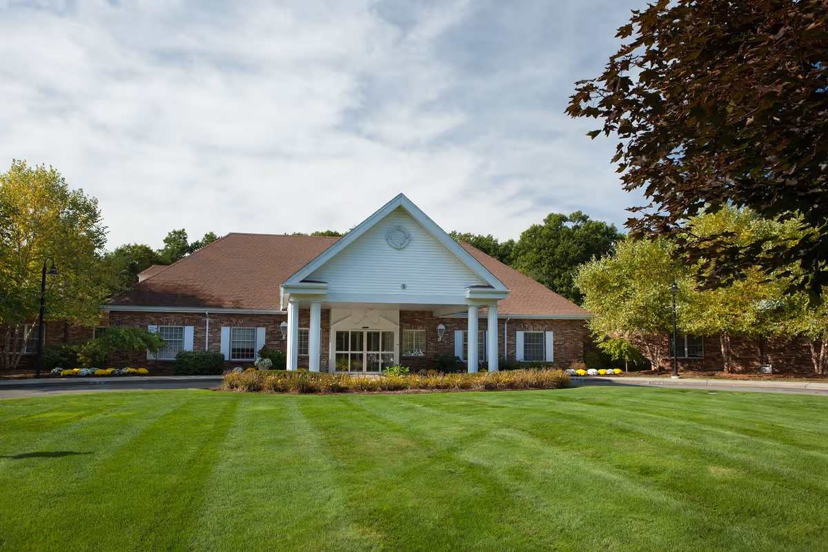 Exterior view of Chestnut Hill, a brick senior living facility with a white-column entrance.
