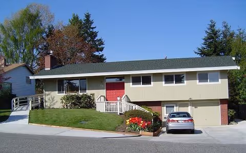 Two-story beige building with a red front door and a driveway.