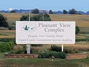 Outdoor sign for Pleasant View Nursing Home in a rural open field.