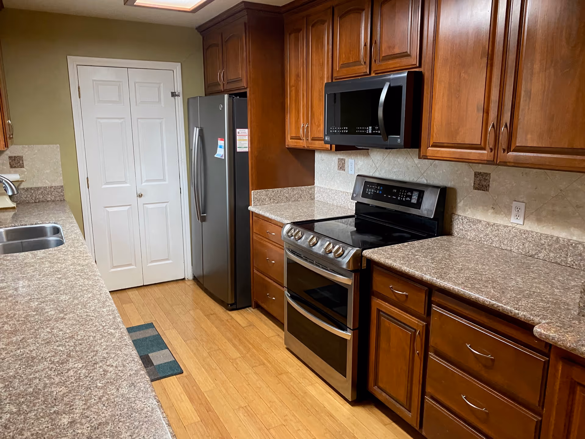 Bright kitchen with stainless appliances, granite counters, and wooden cabinets in a senior living facility.
