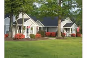 Front view of Bayberry Retirement Inn cottages with green lawn and red shrubs.