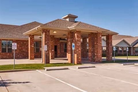 Brick senior living facility entrance with a covered porte-cochere and handicap parking.
