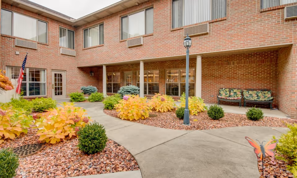 Brick courtyard with landscaped plant beds, a lamppost, benches and ground-floor windows of the facility.
