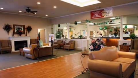 Spacious senior living lobby with beige leather seating, fireplace, and reception area.