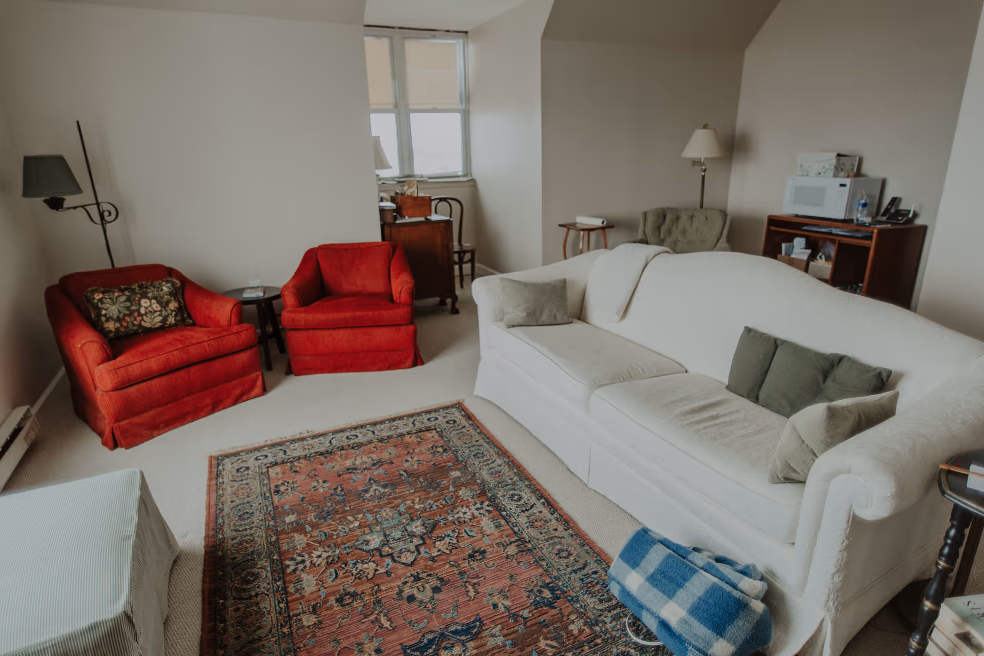 Living room with a white sofa, two red armchairs, a patterned area rug, and small side tables.