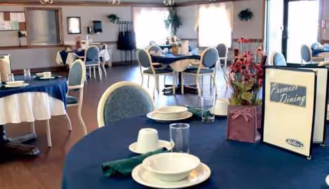 Bright dining room in Miller's Merry Manor VII with round tables and blue upholstered chairs.