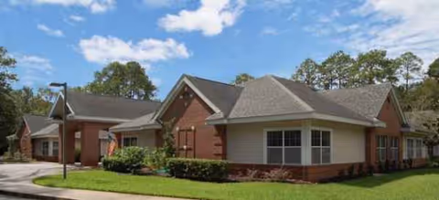 Exterior view of Brookdale Crown Point facility with brick walls, gray roof, and manicured lawn.