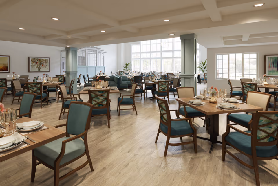 Bright, spacious dining room with multiple set tables and teal-upholstered chairs in a senior living facility.