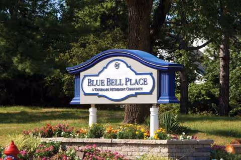 Blue Bell Place sign with flower bed and trees in a landscaped front yard.