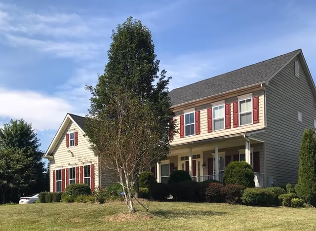Exterior view of a two-story senior living facility with beige siding and red shutters.