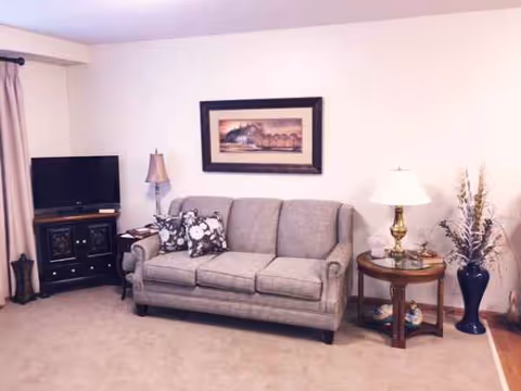 Grey sofa with side tables, lamps, and TV in a cozy living room.