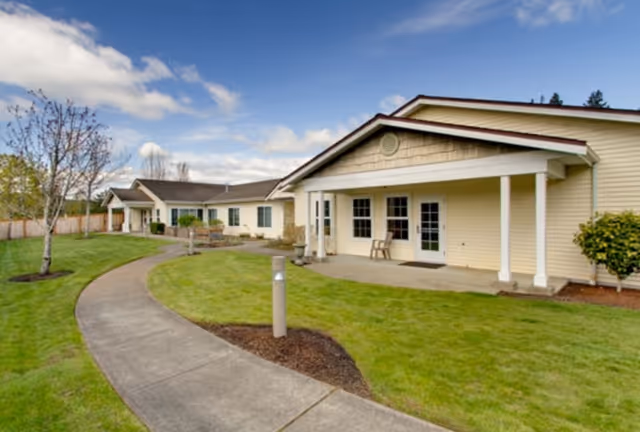 Exterior view of Orchard Pointe by Cogir with a curved walkway and beige building.