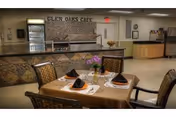Table set for four with folded napkins and a small flower centerpiece in a dining area in front of a counter labeled 'Glen Oaks Cafe'.