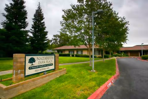 Exterior view of a single-story senior living campus with sign and driveway.