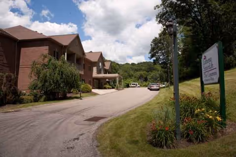 Exterior view of a senior living building with a curved driveway and landscaped lawn.