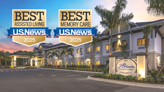 Exterior front of the Atrium at Liberty Park assisted living building at dusk with two U.S. News 'Best' award badges overlaid.