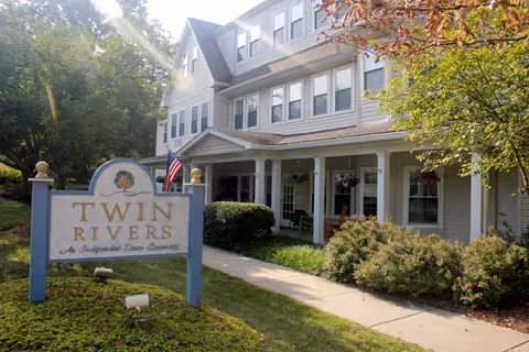 A two-story senior living facility with a sign reading Twin Rivers in front.